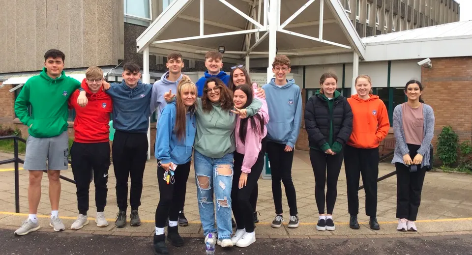 Un gruppo di studenti e studentesse si trova davanti al caratteristico edificio della Currie Community High School.