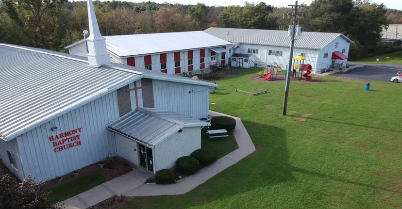 L'edificio della Harmony Christian School si trova accanto a un parco giochi e a un'area verde con un bosco sullo sfondo.