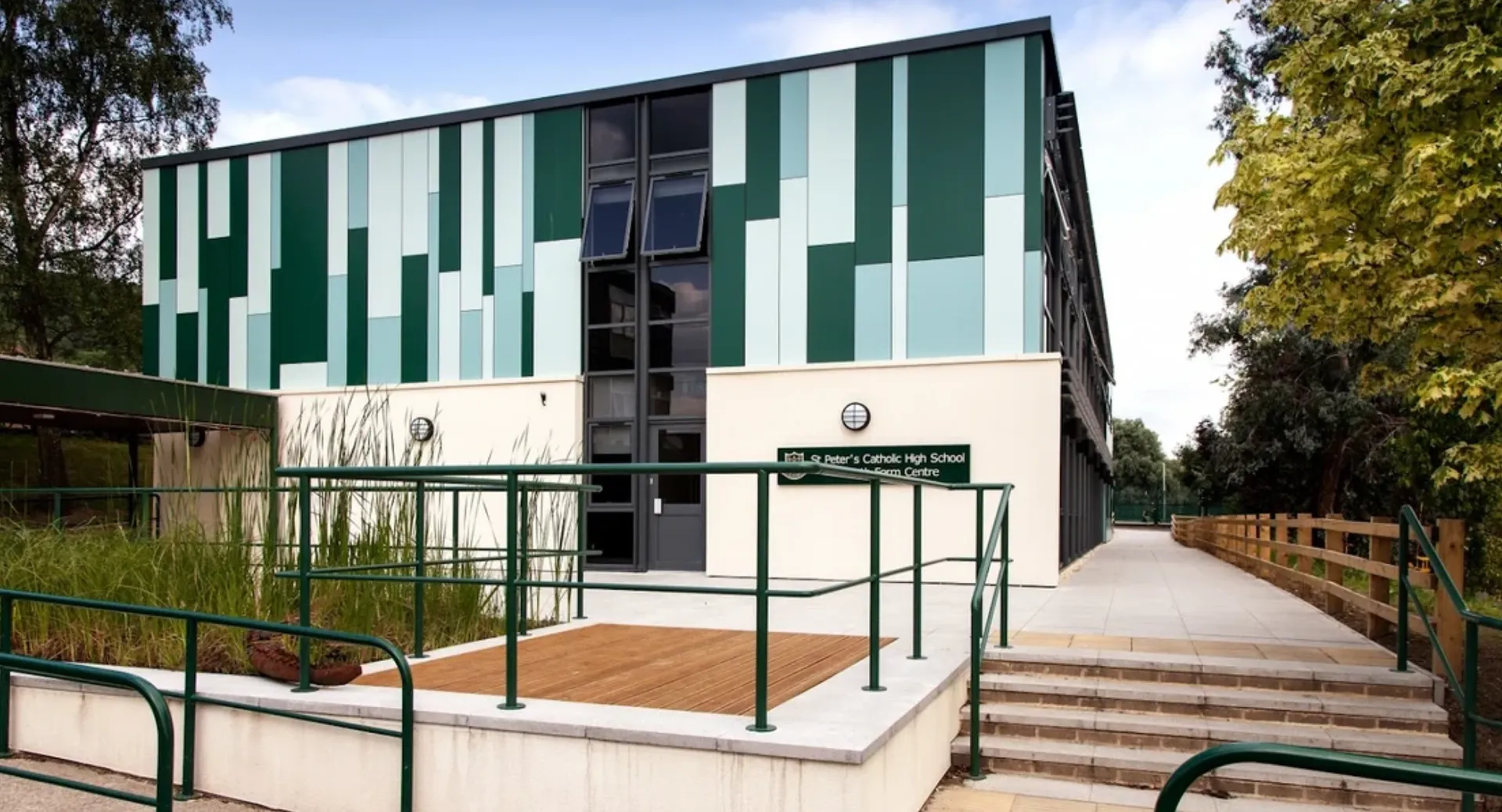 L'edificio moderno a più piani della St. Peter’s High School, con facciata verde e bianca, si trova in un ambiente circondato da alberi.