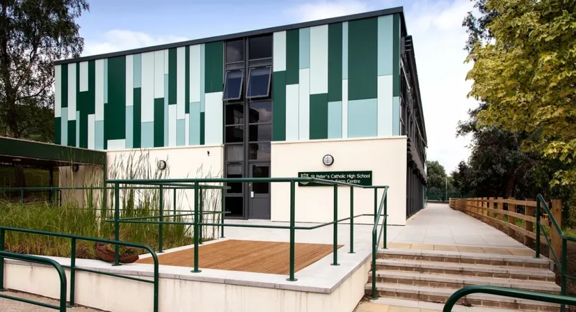 L'edificio moderno a più piani della St. Peter’s High School, con facciata verde e bianca, si trova in un ambiente circondato da alberi.