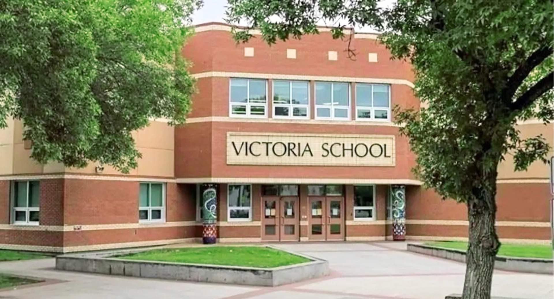 L'edificio in mattoni della Victoria School of the Arts è circondato da alberi verdi e da un prato.