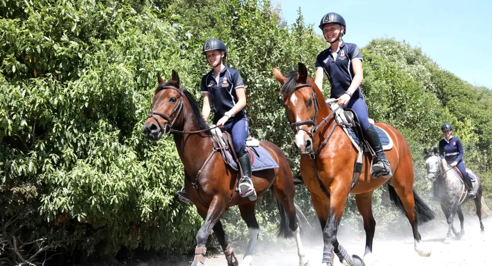 Due persone in uniforme da polizia cavalcano a cavallo in un ambiente verde nei terreni della Nga Tawa Diocesan School.