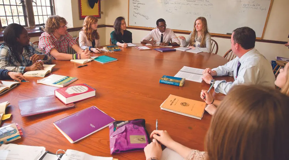 Un gruppo di studenti e un docente di The Masters School lavorano insieme a un grande tavolo in legno in classe.