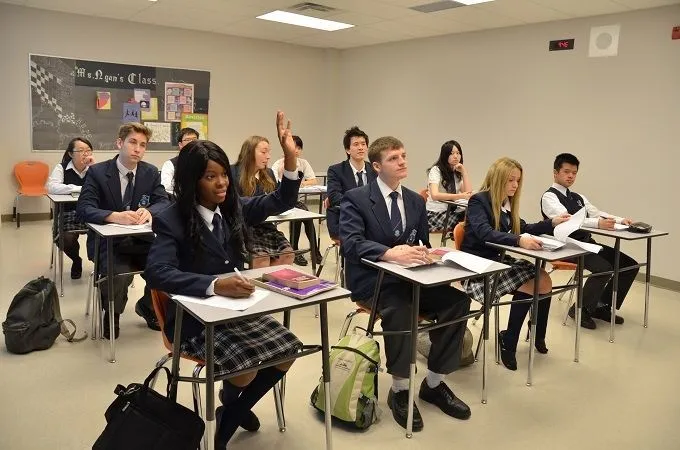 Un grupo de estudiantes de J. Addison School está sentado con uniformes escolares en el aula con materiales didácticos y carteles educativos.