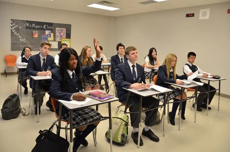 Un gruppo di studenti della J. Addison School siede in divisa scolastica in un'aula con materiale didattico e poster educativi.