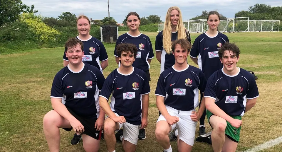Un gruppo di studenti dell'Elizabeth College posa insieme su un campo da calcio con la porta sullo sfondo.
