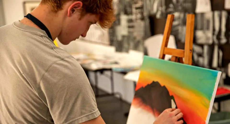 Una persona dipinge un quadro astratto e variopinto nell'atelier della Besant Hill School.