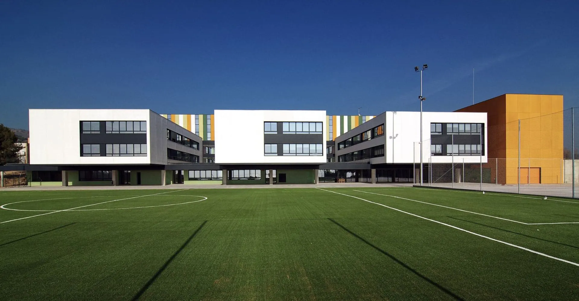 L'edificio moderno della Hamelin-Laie International School con un grande campo sportivo in primo piano sotto un cielo limpido.