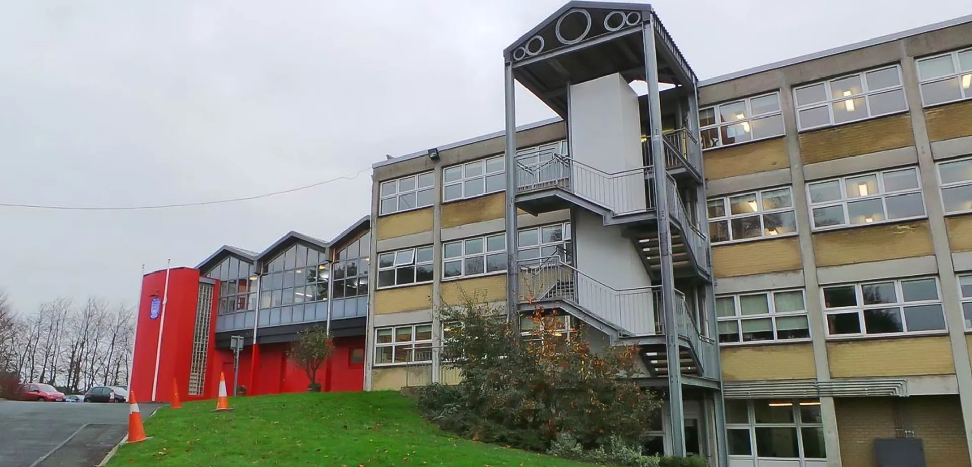 L'edificio a più piani della Mount Sackville Secondary School, con facciata gialla e rossa, è circondato da un'area verde con alberi.