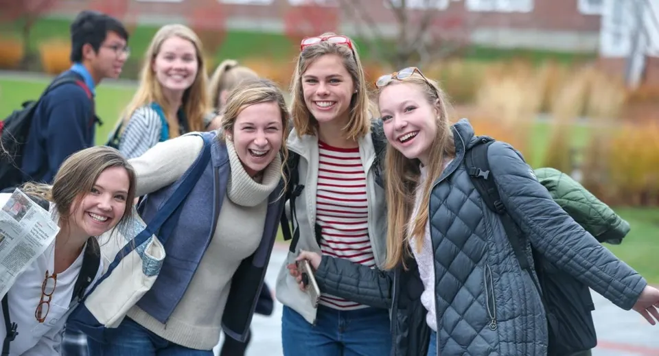 Un gruppo di studenti si trova all'aperto in inverno davanti a edifici in mattoni nel campus della Kimball Union Academy.