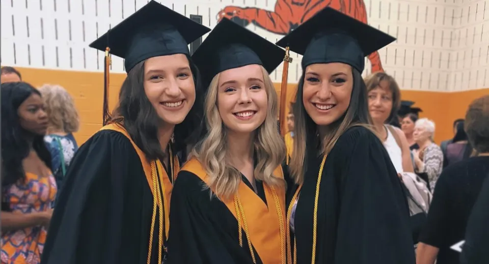 Tre studentesse della St. Matthew High School posano alla cerimonia di diploma con toga e tocco.
