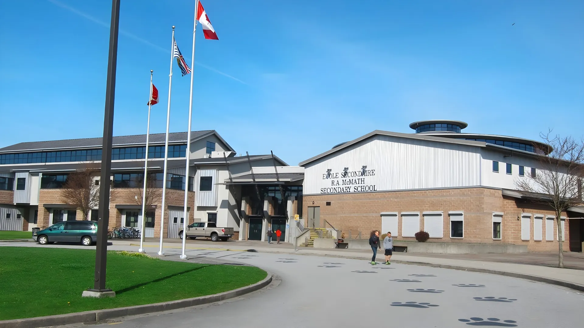 L'edificio moderno a più piani della École Secondaire R.A. McMath Secondary School con bandiere e un vialetto in primo piano.