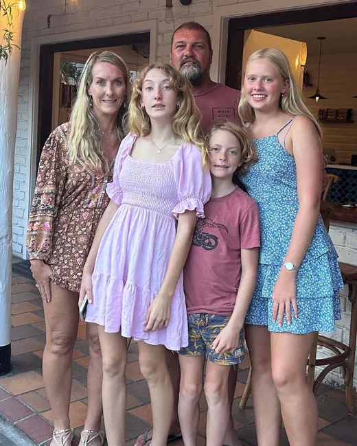 Familia anfitriona de cinco personas posando juntas a la entrada de su casa