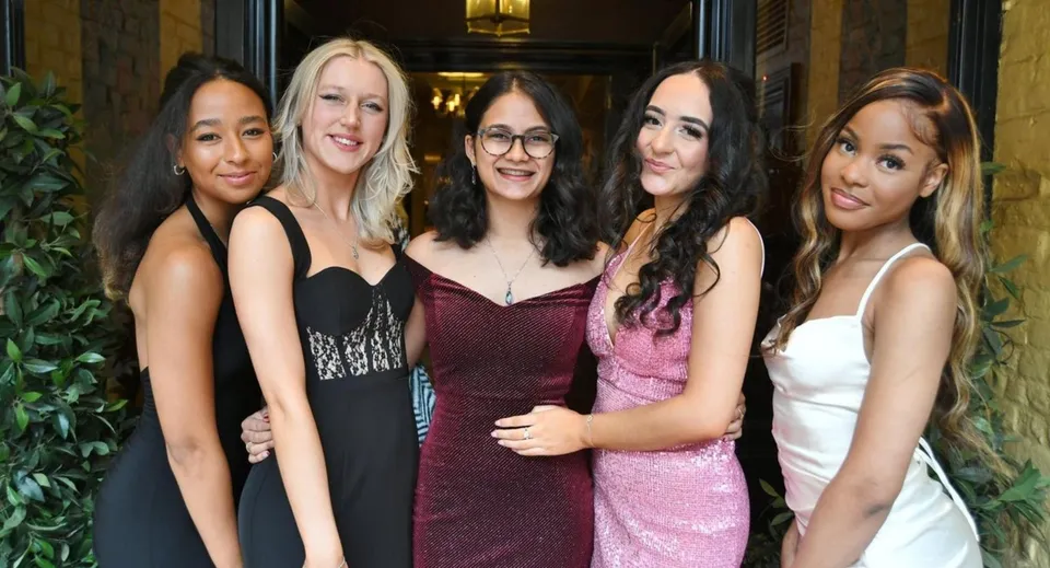 Un gruppo di cinque studentesse in abito formale è insieme nel campus di King's Ely.