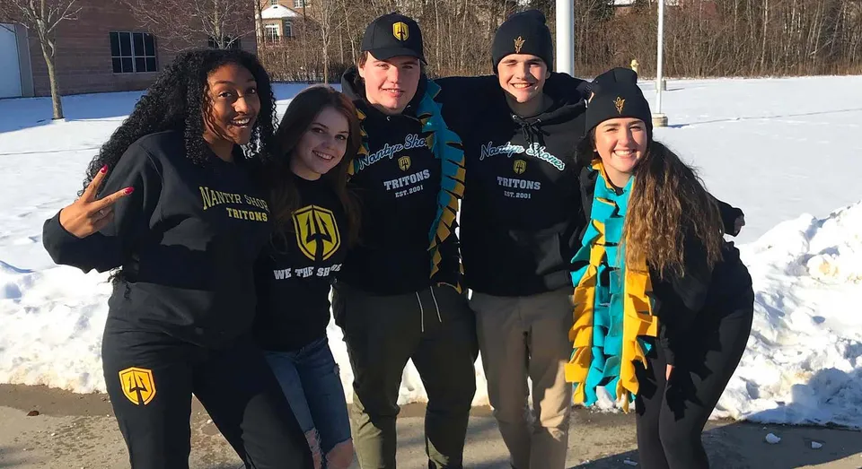 Un gruppo di studenti e studentesse della Nantyr Shores Secondary School è insieme sulla neve con felpe con cappuccio nere.