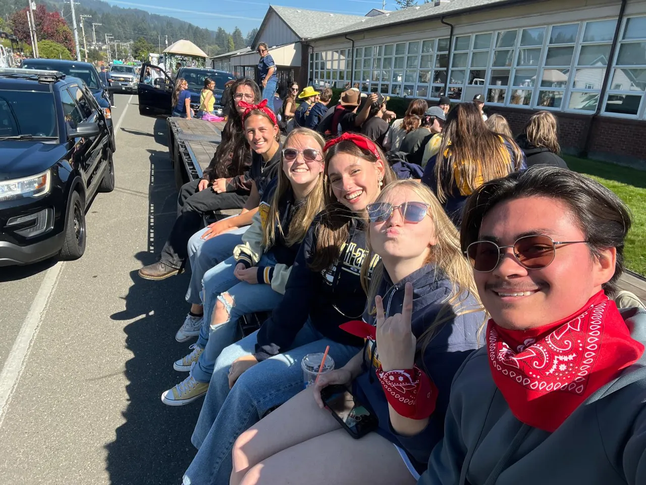 Gruppo di studenti seduti su un rimorchio con bandane rosse durante una parata in una giornata di sole