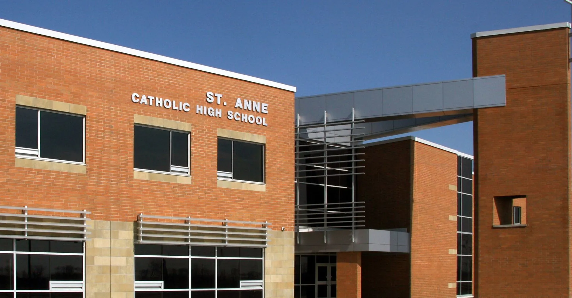 L'edificio moderno in mattoni della St. Anne Catholic High School si staglia contro un cielo azzurro e limpido.