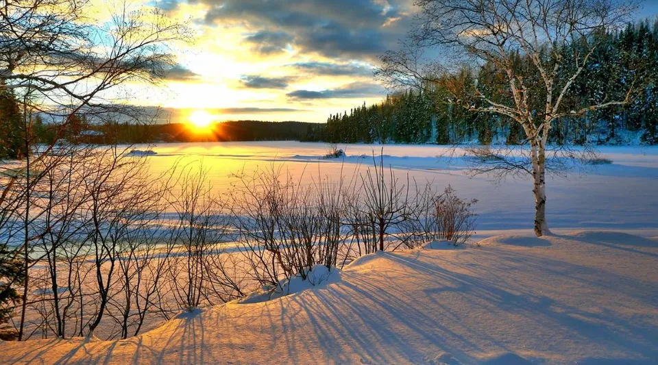 Un paesaggio invernale innevato con un lago ghiacciato e un tramonto vicino alla Haliburton Highlands School.