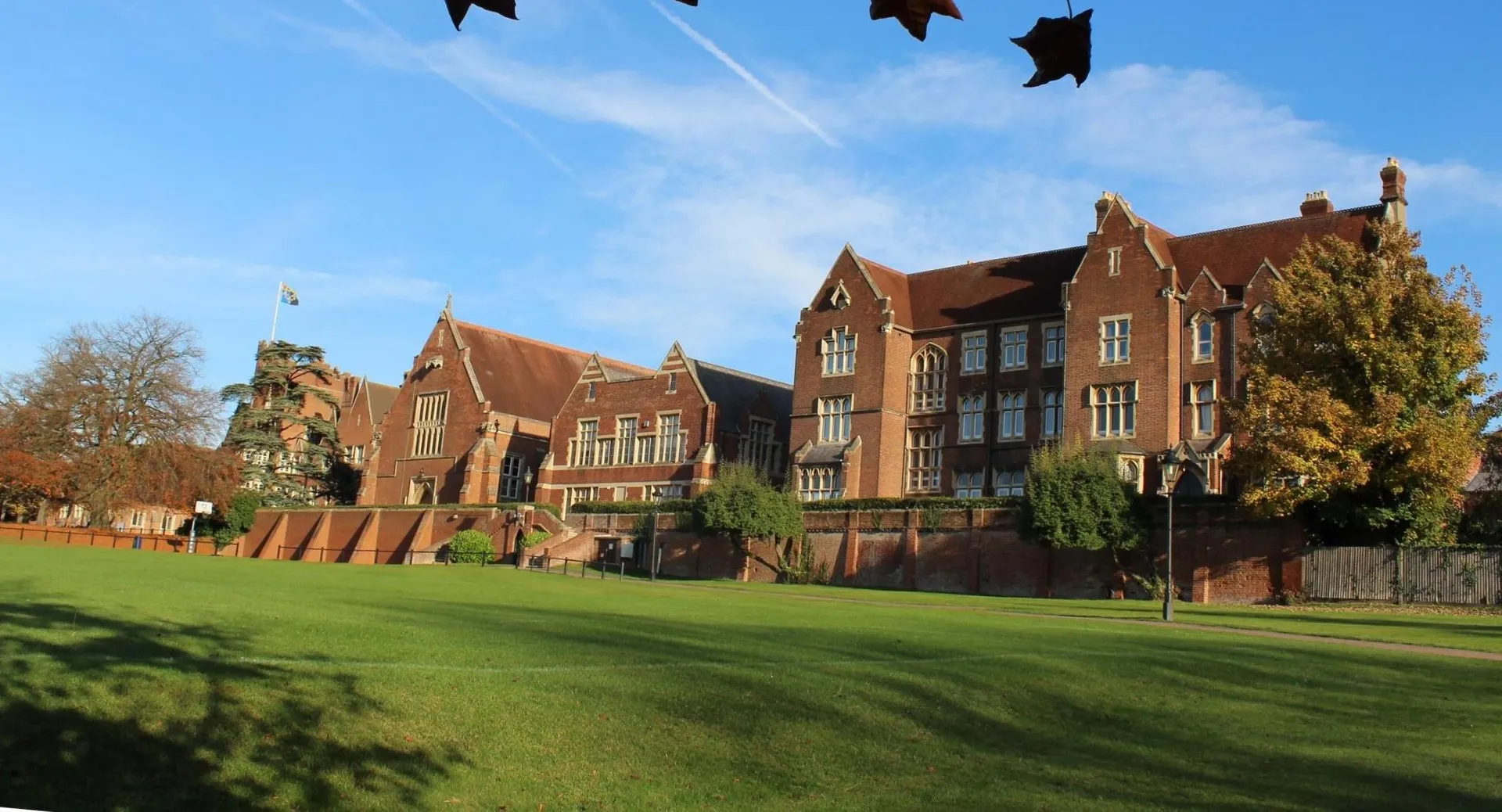 L'edificio principale storico dell'Epsom College sorge nel vasto campus con un prato curato e alberi autunnali sullo sfondo.