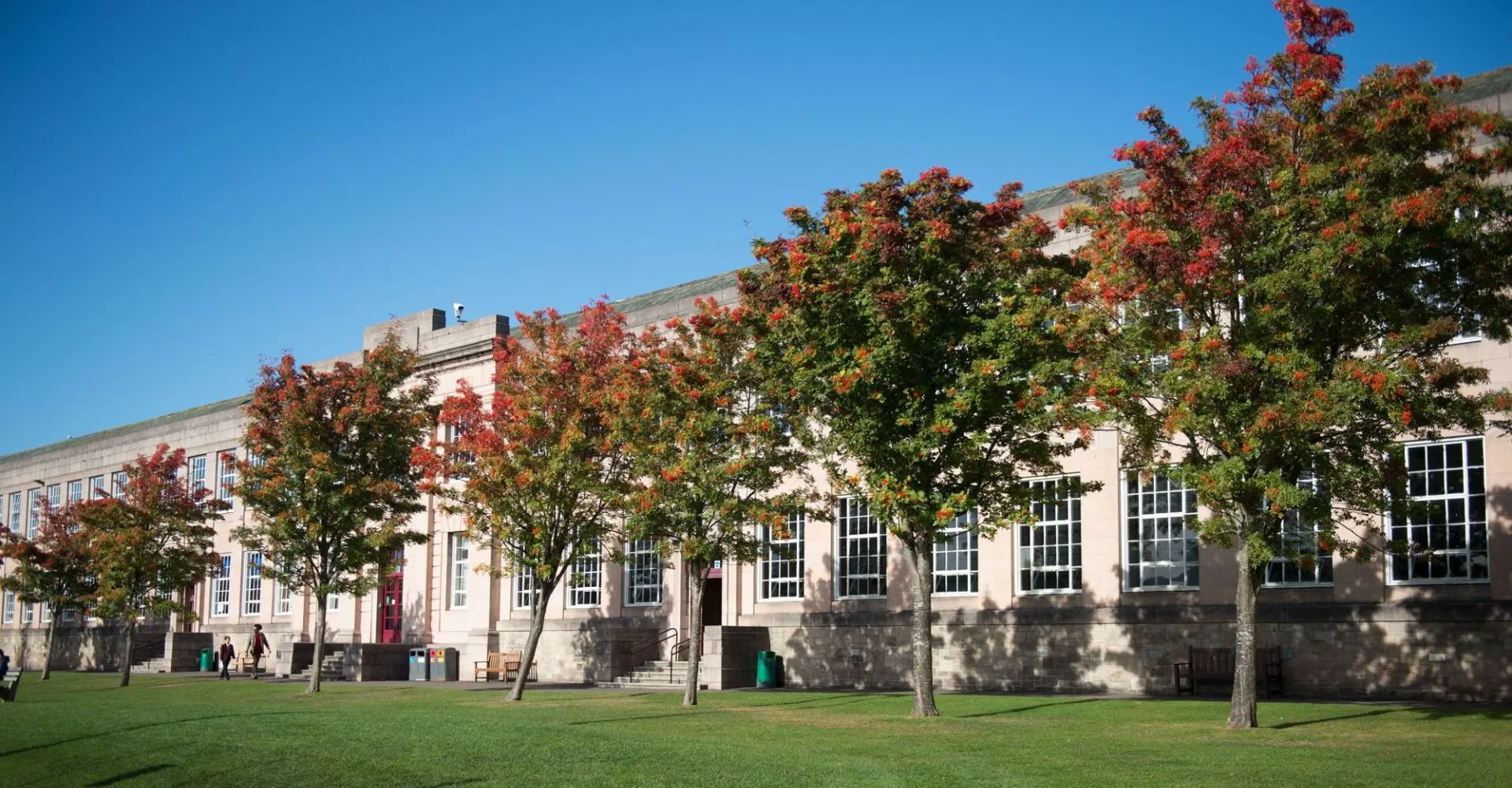 Il campus del George Watson’s College mostra un prato erboso e edifici davanti ad alberi dai colori autunnali.