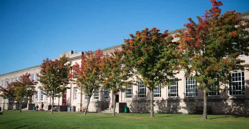 Il campus del George Watson’s College mostra un prato erboso e edifici davanti ad alberi dai colori autunnali.