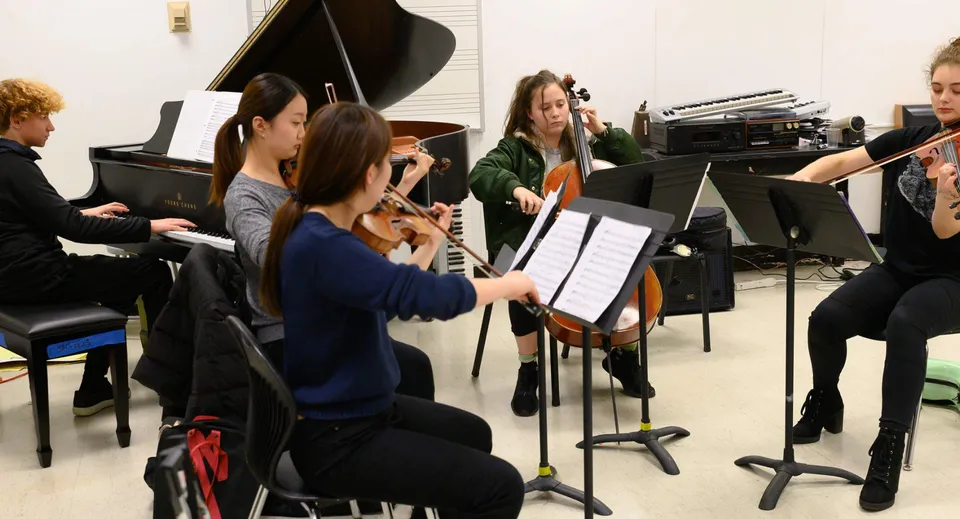 Un gruppo di studenti della Moyne Community School prova insieme con strumenti musicali in un'aula.