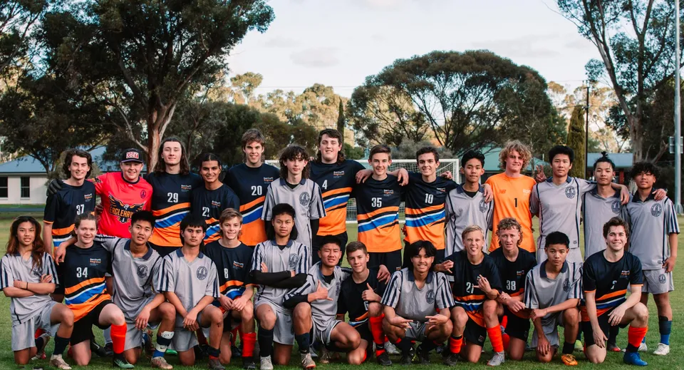 Un gruppo di giovani calciatrici e calciatori posa nel parco all'interno del terreno della Mount Gambier High School.