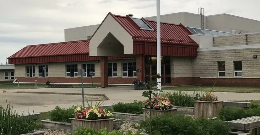 L'edificio della Forestburg School con un tetto in metallo rosso e fioriere in primo piano.