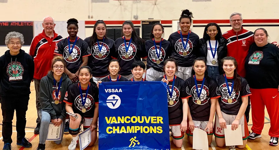 Un gruppo di giovani atlete della Britannia Secondary School tiene in una palestra uno striscione con la scritta Vancouver Champions.