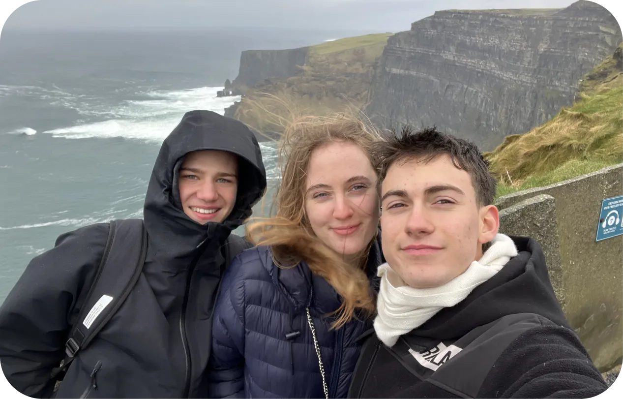 Selfie de tres estudiantes abrigados ante los acantilados de Moher