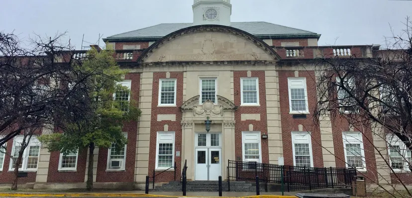 L'edificio in mattoni con torre dell'orologio della Stamford High School è circondato da alberi spogli e da una recinzione in ferro battuto.