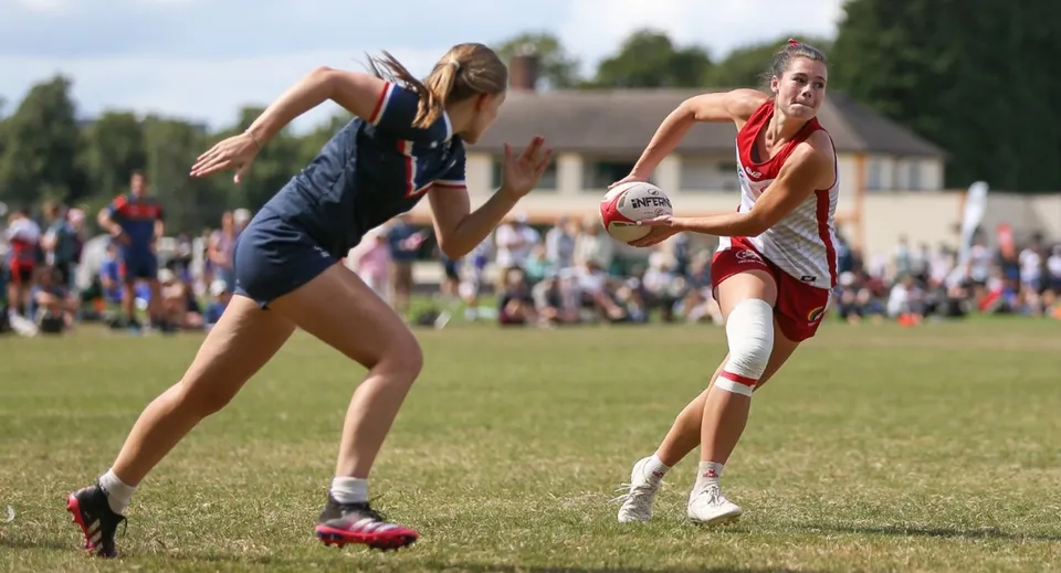 Due atlete della Brighton Girls lottano per il pallone sul campo da calcio davanti alle tribune degli spettatori.