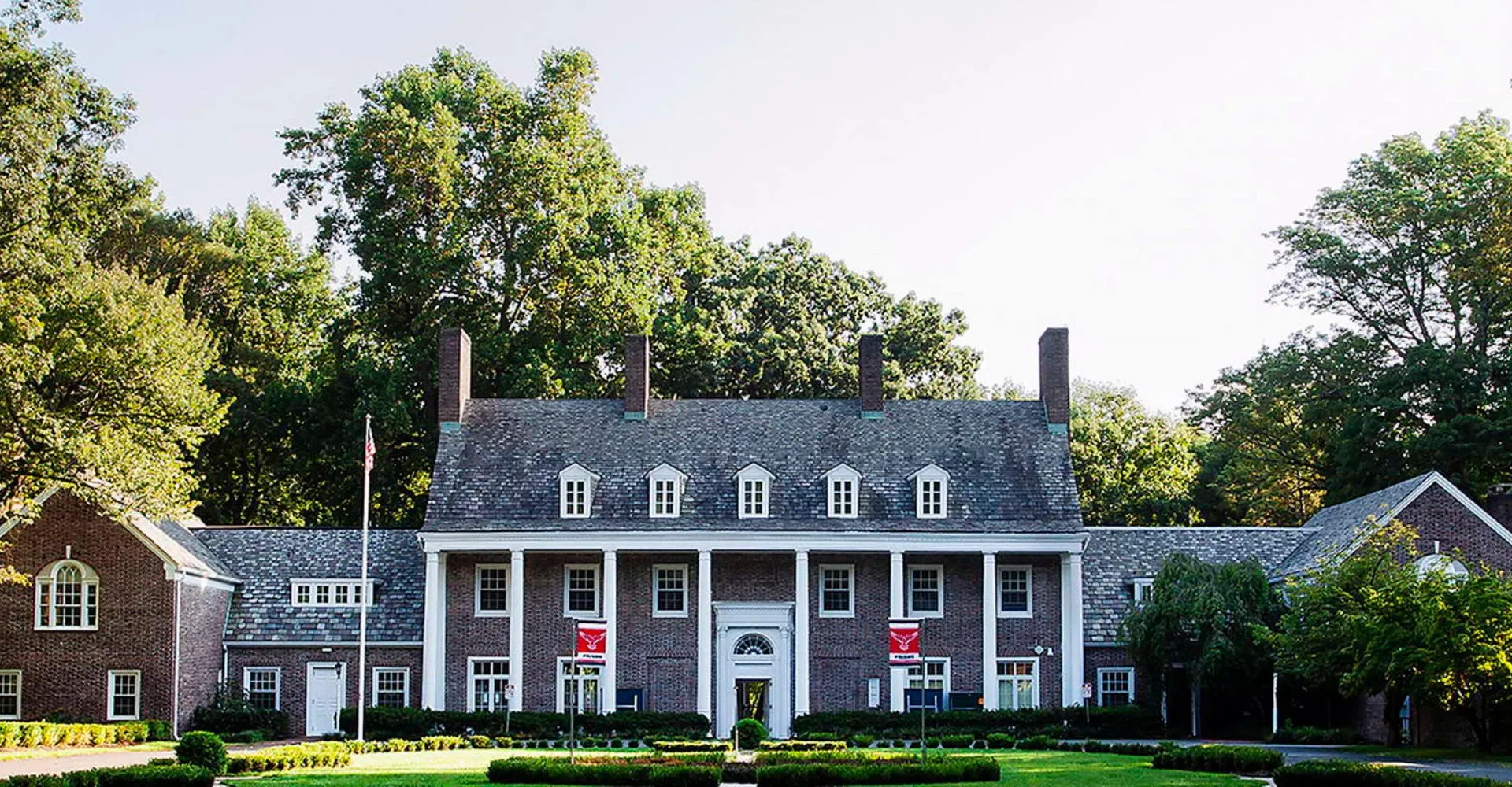 Una villa in stile coloniale sorge nel campus della Princeton International School of Mathematics & Science, circondata da alberi e un prato ben curato.