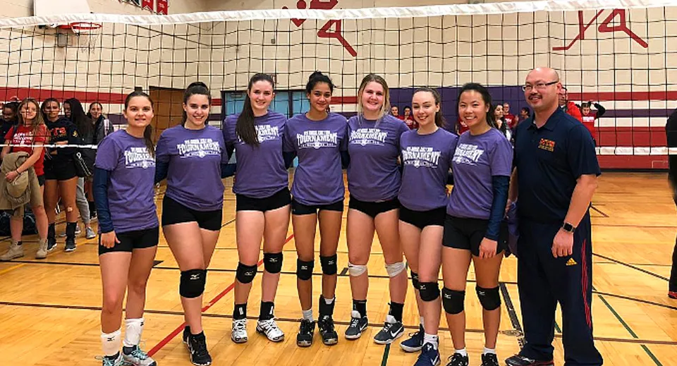 Un gruppo di pallavoliste in divisa viola si trova sul campo da pallavolo del Sir John A. Macdonald Collegiate Institute.