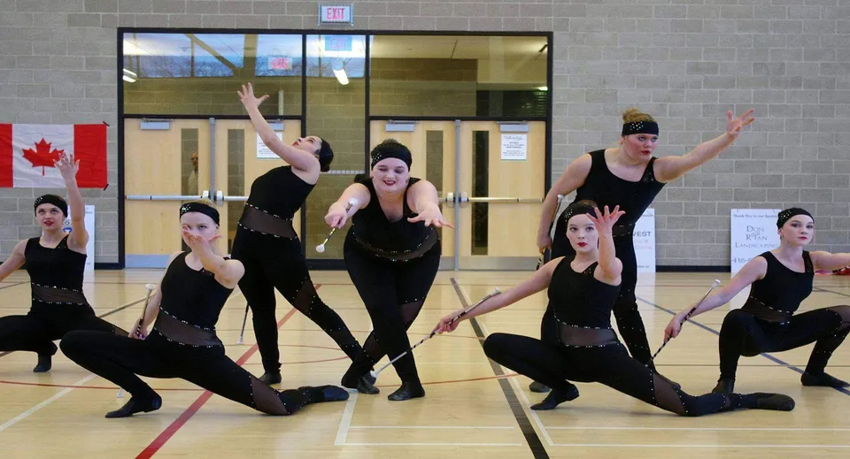 Un gruppo di danza della King City Secondary School esegue una coreografia sincronizzata davanti a una parete di mattoni al coperto.