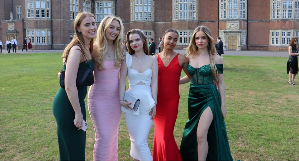 Un gruppo di giovani donne in abito formale posa davanti allo storico edificio in mattoni del Wrekin College.