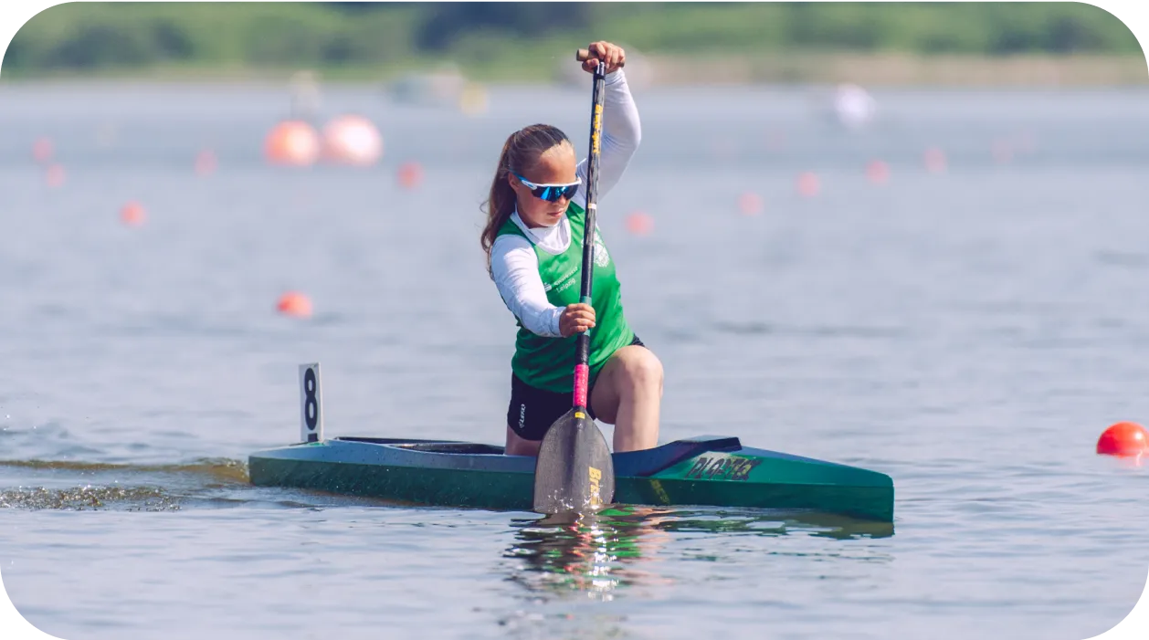 Chica remando en una canoa de competición sobre un lago