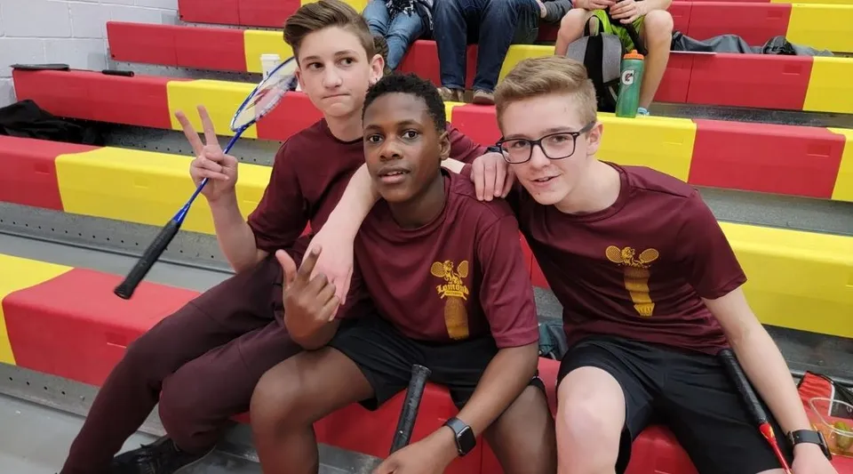 Tre studenti della Lomond Community School posano insieme nella palestra con tappetini colorati sullo sfondo.