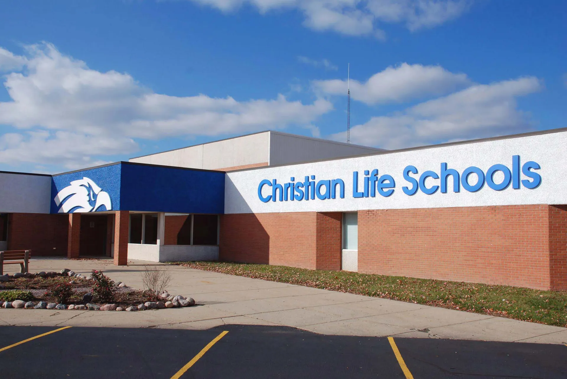 L'edificio della Christian Life School mostra una facciata in mattoni con l'insegna della scuola su uno sfondo di cielo blu con nuvole.