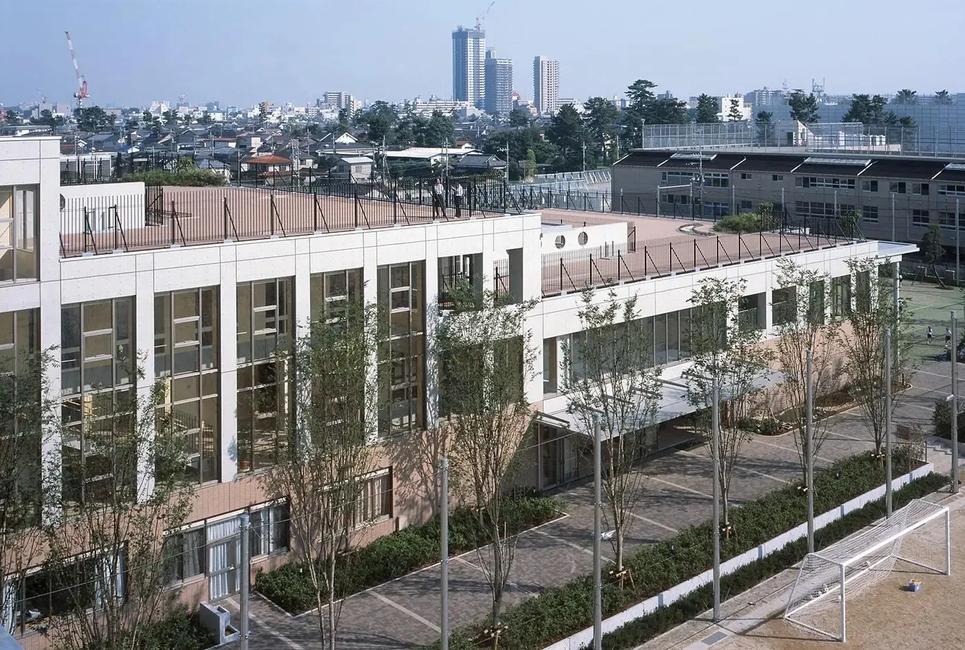 Das moderne Schulgebäude der Hinodegakuen Senior High School mit Dachterrasse, Innenhof und Blick auf die Stadt.