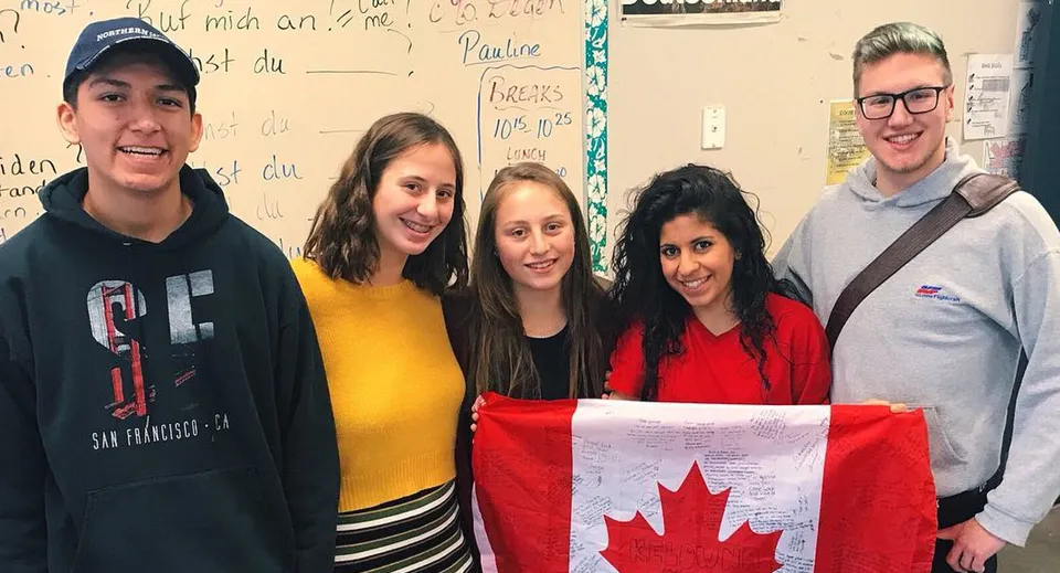 Studenti della Rutland Senior Secondary School tengono insieme la bandiera canadese in un'aula.