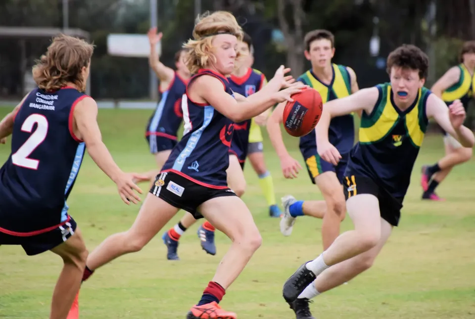 Studenti del Cathedral College Wangaratta giocano a football australiano su un campo d'erba.