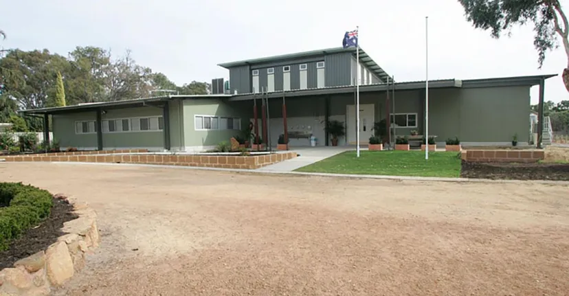 L'edificio scolastico moderno a un piano della Kelmscott Senior High School è circondato da alberi e aree verdi.