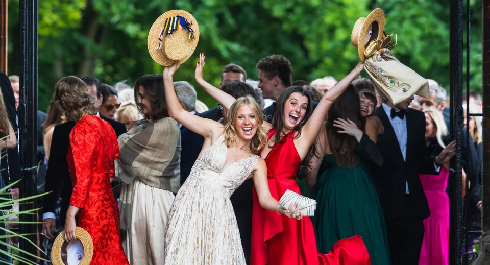 Un gruppo di studenti del Wellington College festeggia insieme nel campus della scuola circondato dal verde.