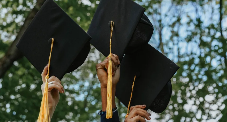 Due tocchi da laurea neri con nappe dorate vengono tenuti in alto nel campus del Walkerville Collegiate Institute.