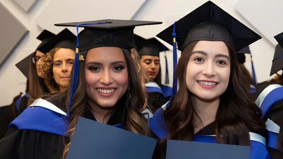 Un gruppo di giovani donne in abito da diploma festeggia i propri diplomi nel campus della École Salish Secondary School.