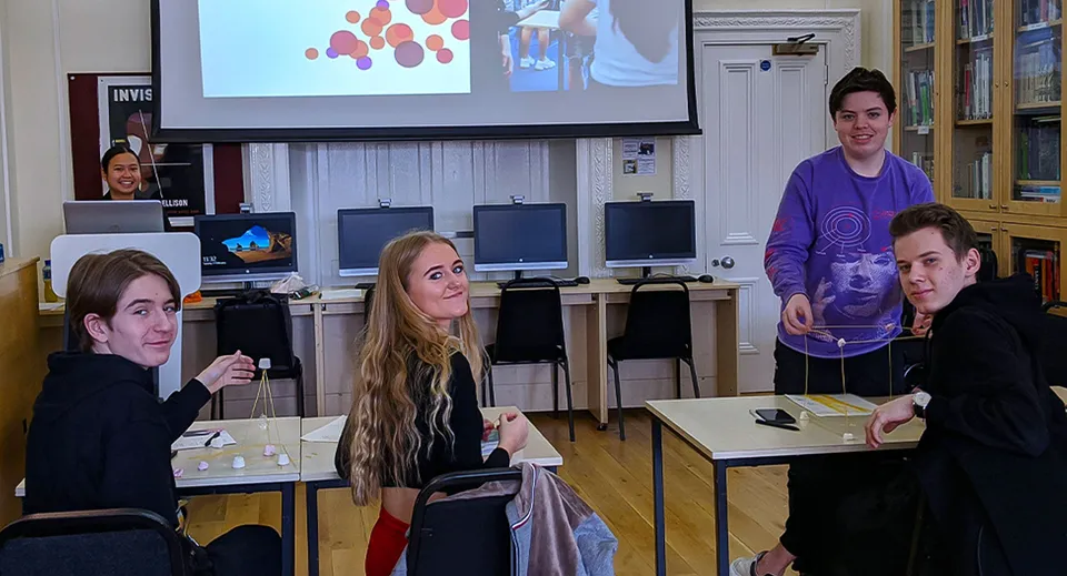 Gli studenti della MPW London osservano una grafica a colori su uno schermo di proiezione in classe.