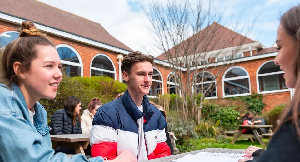 Studenti chiacchierano in una giornata di sole davanti a un edificio in mattoni nel campus del Varndean College.