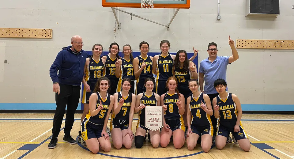 Un gruppo di giovani giocatrici di basket posa insieme sul campo della Kalamalka Secondary School.