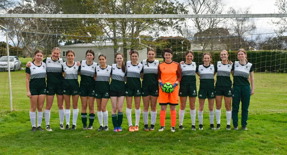 Un gruppo di giovani calciatrici si trova insieme sul campo sportivo del Solway College.
